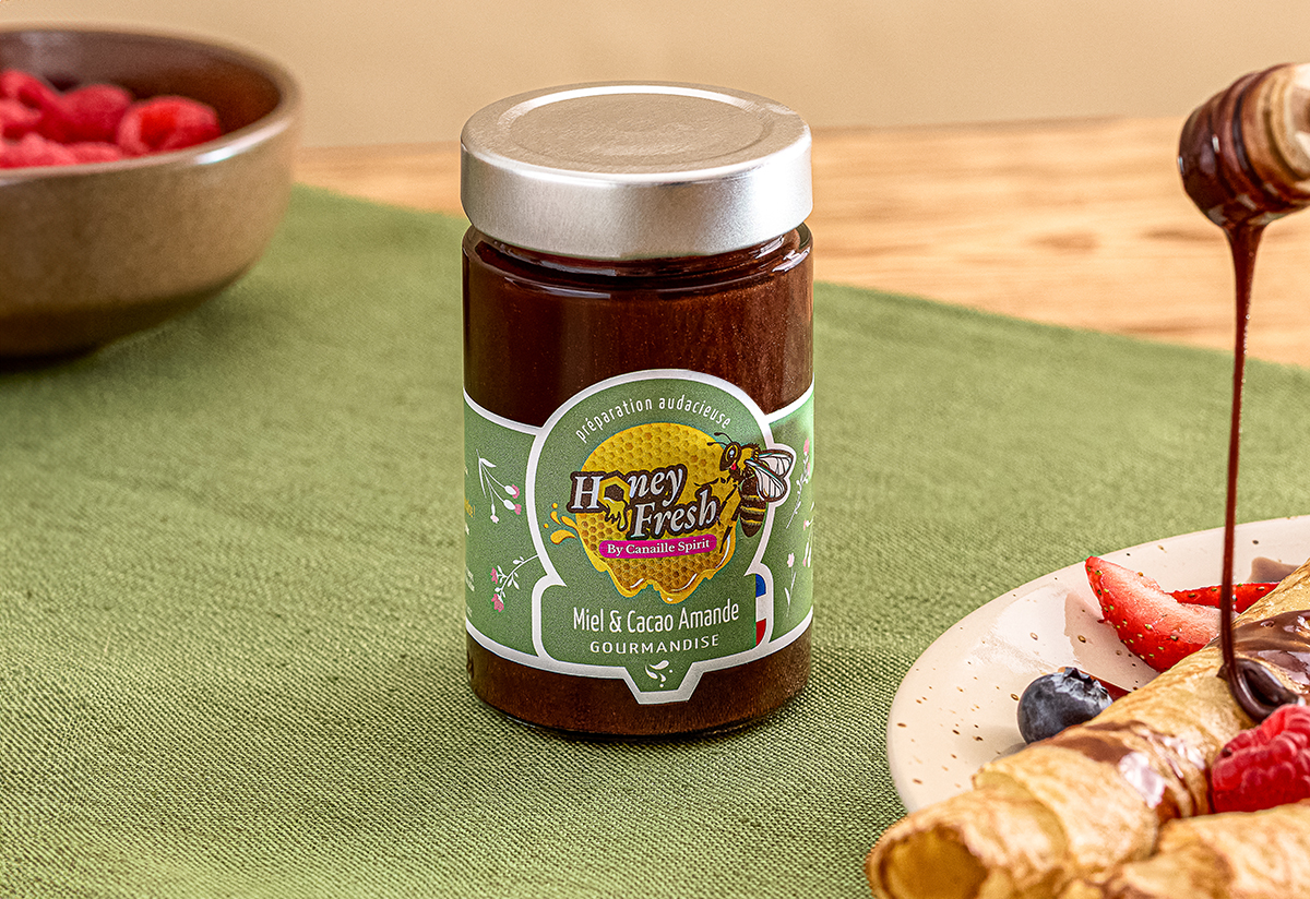 Photo du pot Honey Fresh Miel & &cacao Amande, ambiance naturel dans les tons verts et bois avec une assiète gourmande de crèpes.